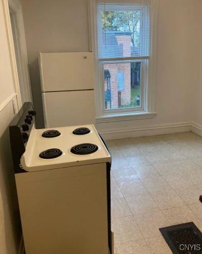kitchen featuring baseboards and white appliances