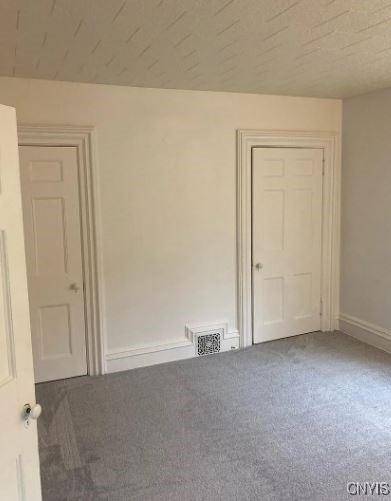 carpeted spare room featuring baseboards and visible vents