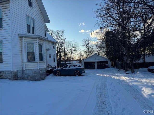 view of snow covered exterior with an outbuilding and a garage