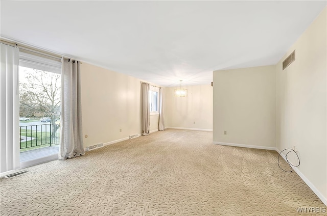 carpeted empty room featuring a chandelier