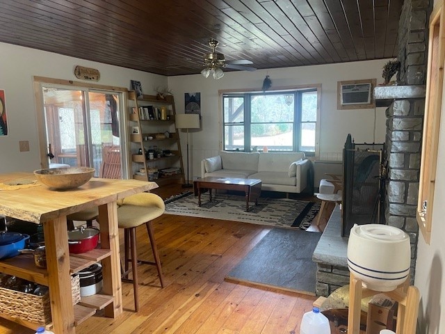 dining space with wooden ceiling, ceiling fan, light wood-type flooring, a fireplace, and a wall unit AC