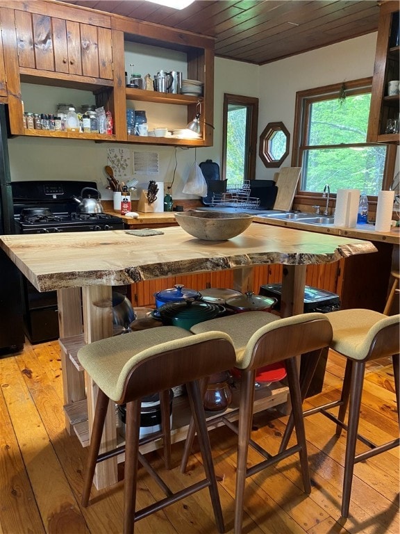 kitchen with a kitchen breakfast bar, light wood-type flooring, wooden ceiling, butcher block countertops, and a kitchen island