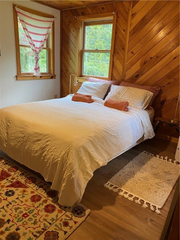 bedroom with wood-type flooring and wooden walls