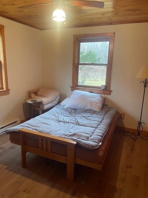 bedroom featuring baseboard heating, ceiling fan, hardwood / wood-style floors, and wooden ceiling