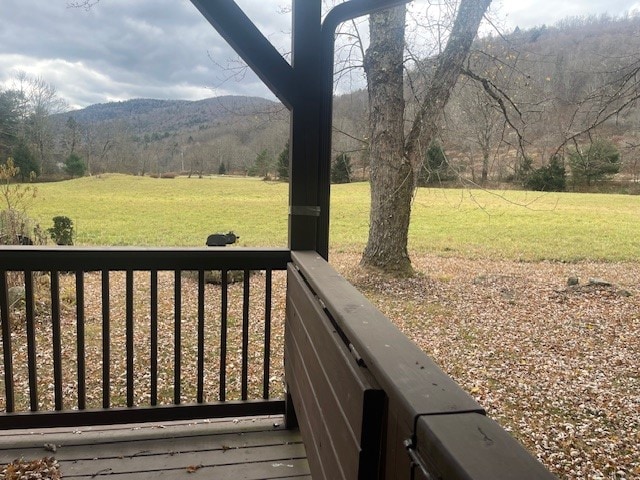 wooden deck featuring a mountain view and a yard