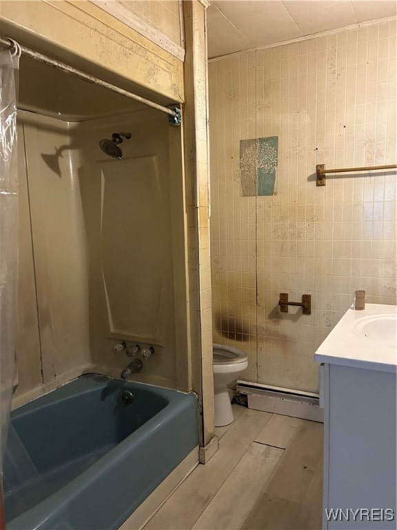 full bathroom with toilet, baseboard heating, and tile walls