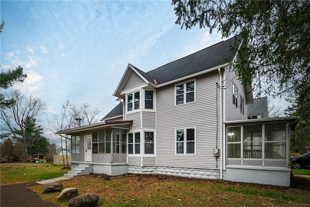 rear view of property with a sunroom and a lawn