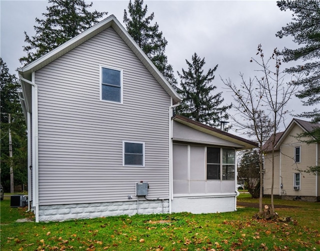 view of property exterior featuring a sunroom, central air condition unit, and a lawn