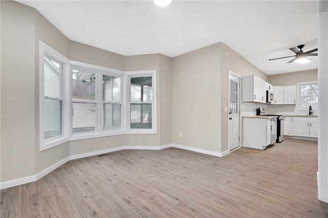 kitchen featuring appliances with stainless steel finishes, ceiling fan, sink, light hardwood / wood-style flooring, and white cabinets