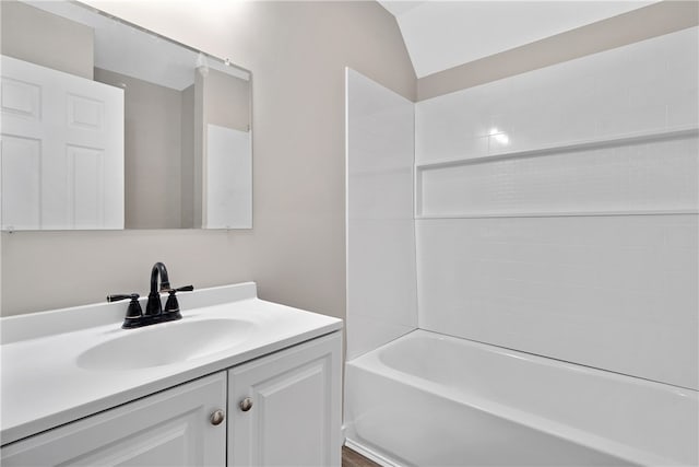 bathroom with vanity, washtub / shower combination, and vaulted ceiling