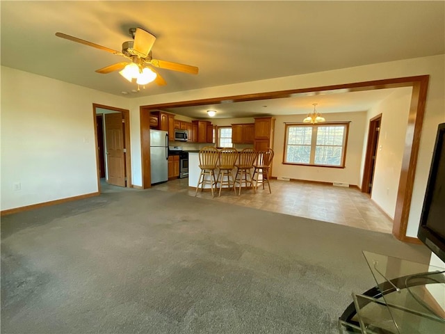 unfurnished living room featuring baseboards, a ceiling fan, and light colored carpet