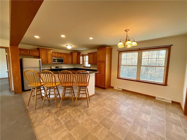 kitchen featuring stainless steel appliances, dark countertops, brown cabinets, and recessed lighting