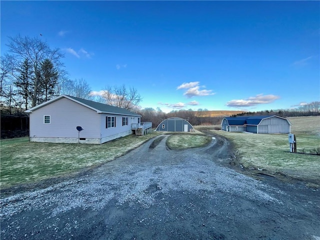 view of side of property with dirt driveway and an outdoor structure