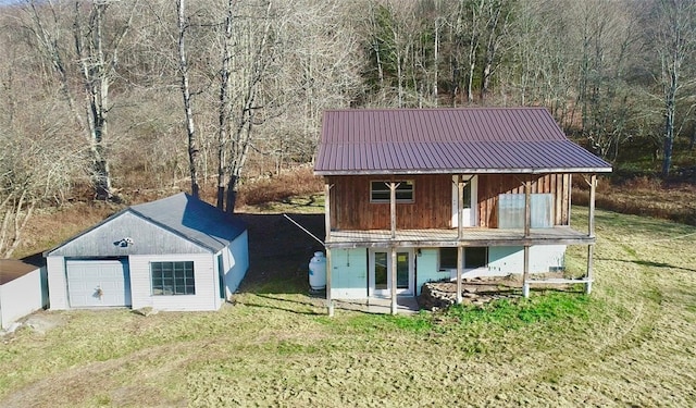 back of property featuring a lawn, a garage, and an outbuilding