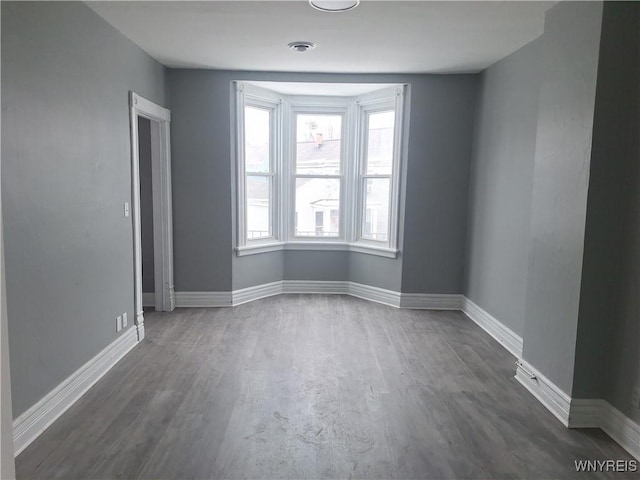 unfurnished room featuring dark wood-style flooring, visible vents, and baseboards