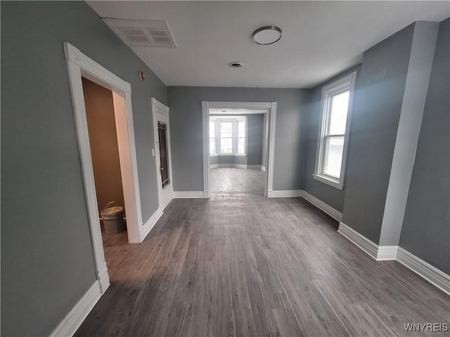 corridor with dark wood-style flooring, visible vents, and baseboards