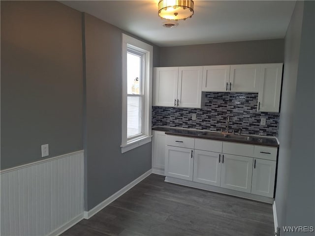 kitchen featuring dark countertops, dark wood finished floors, white cabinetry, and a sink