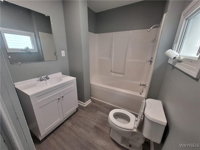 bathroom featuring shower / tub combination, toilet, wood finished floors, vanity, and baseboards