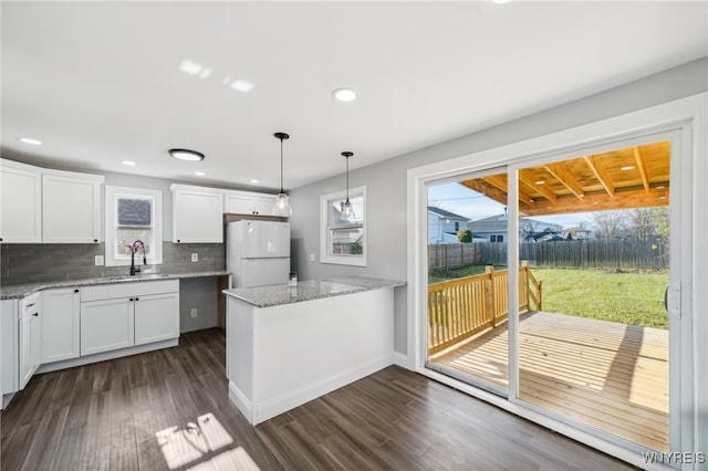 kitchen featuring white cabinets, white fridge, tasteful backsplash, and dark wood-type flooring