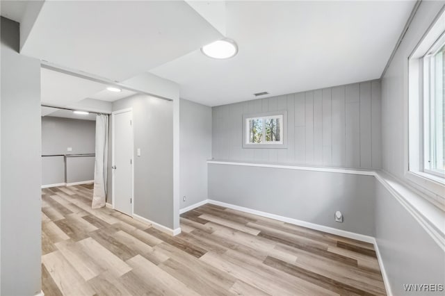 basement with wooden walls and light hardwood / wood-style flooring