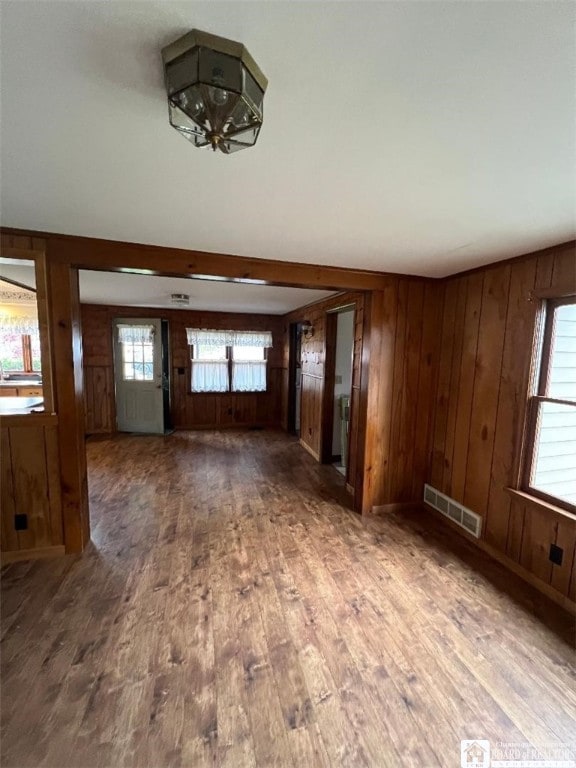 unfurnished living room featuring hardwood / wood-style flooring, a healthy amount of sunlight, and wood walls