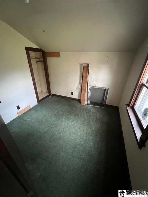 carpeted empty room featuring vaulted ceiling