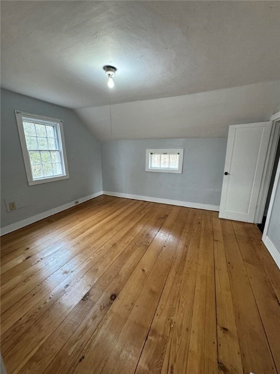 bonus room with lofted ceiling and light wood-type flooring