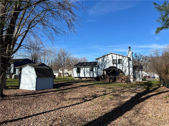 view of property exterior with a gazebo, a wooden deck, and a storage shed