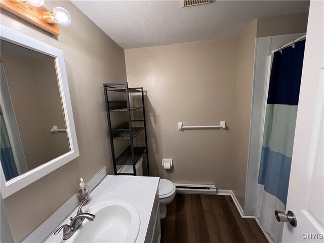 bathroom featuring vanity, a textured ceiling, baseboard heating, hardwood / wood-style flooring, and toilet