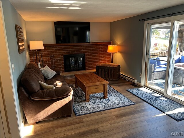 living room with hardwood / wood-style flooring, a fireplace, and a baseboard heating unit