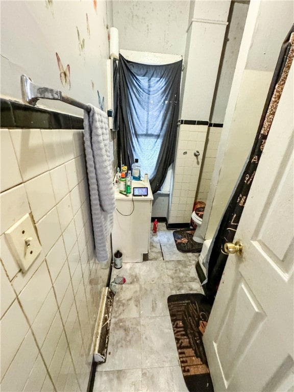 bathroom featuring toilet and tile walls