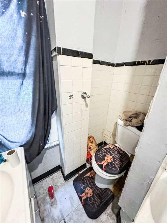 bathroom featuring toilet and tile walls