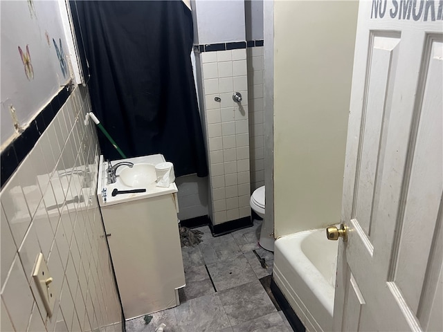 bathroom featuring vanity, toilet, and tile walls