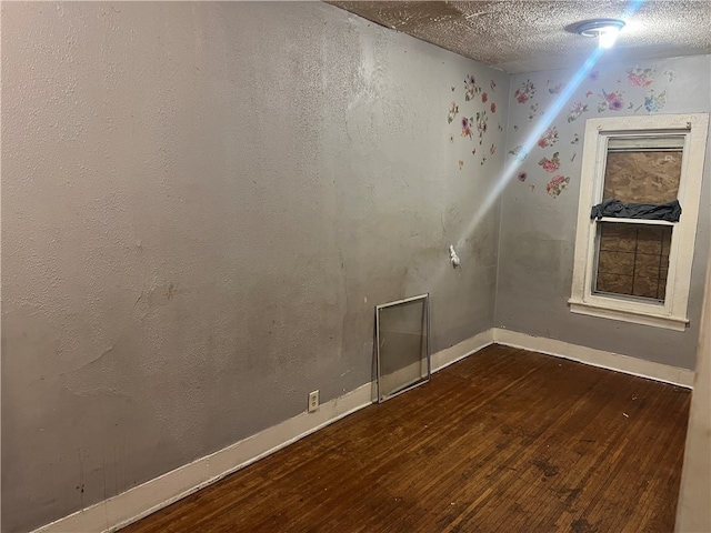 empty room with dark hardwood / wood-style flooring and a textured ceiling