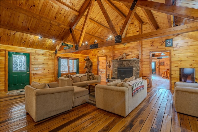 living room with hardwood / wood-style flooring, a stone fireplace, wooden ceiling, and wooden walls