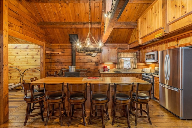 kitchen featuring hardwood / wood-style floors, vaulted ceiling with beams, wooden ceiling, and stainless steel appliances