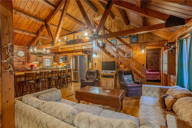 living room with vaulted ceiling with beams, wooden walls, and light hardwood / wood-style flooring