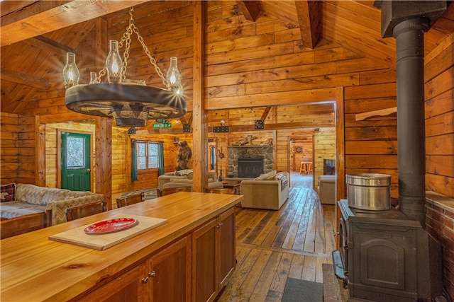 kitchen featuring wood walls, a wood stove, vaulted ceiling with beams, dark hardwood / wood-style flooring, and butcher block counters