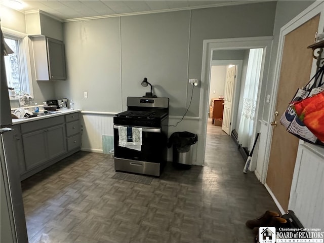 kitchen with gray cabinetry, crown molding, dark parquet floors, and stainless steel stove