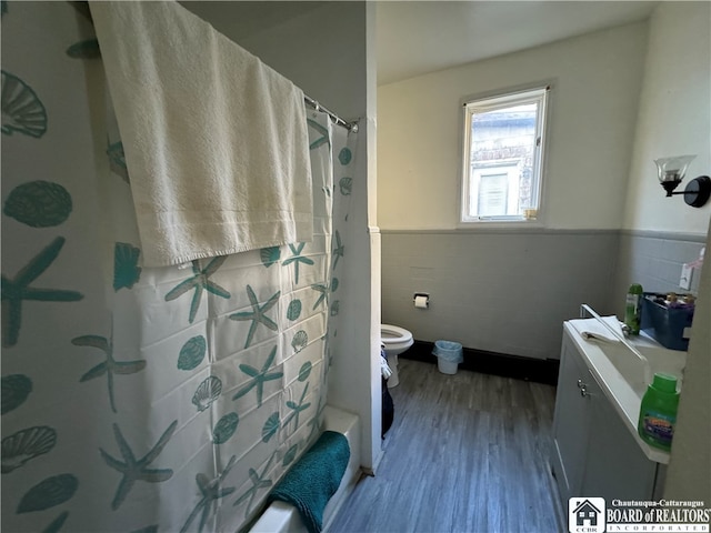 bathroom featuring hardwood / wood-style floors, toilet, tile walls, and walk in shower