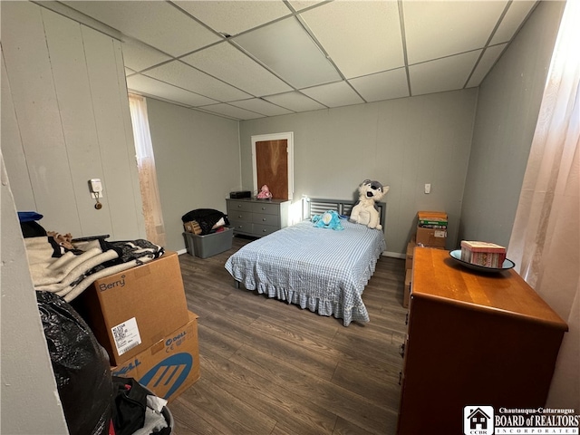 bedroom with a paneled ceiling and dark hardwood / wood-style flooring