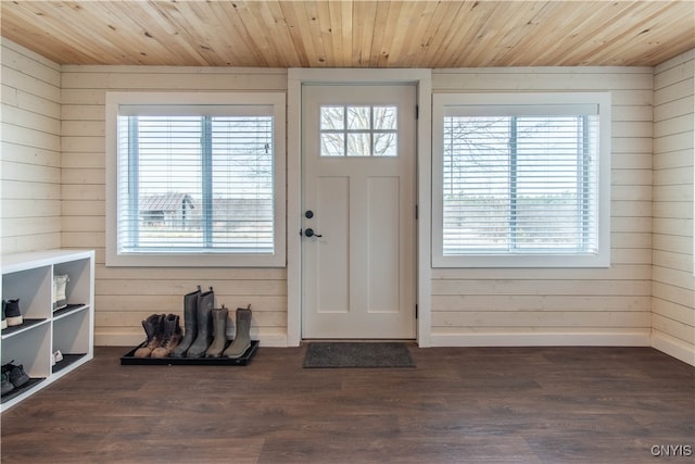 foyer entrance with dark hardwood / wood-style floors, wood ceiling, and wooden walls