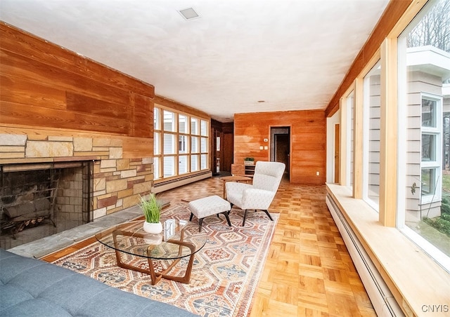 living room featuring light parquet flooring, a baseboard radiator, plenty of natural light, and wood walls