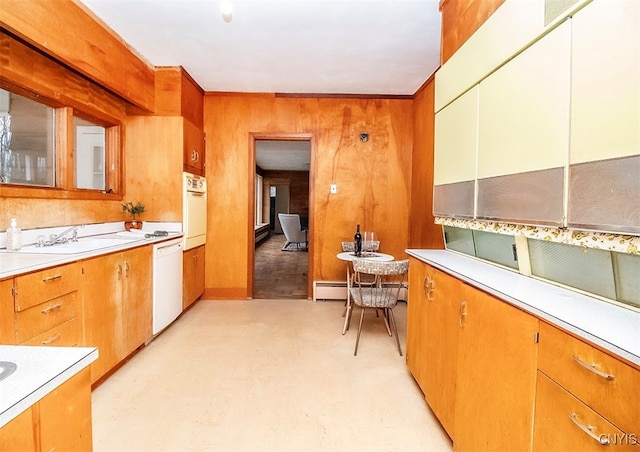 kitchen featuring white appliances, baseboard heating, wooden walls, and sink