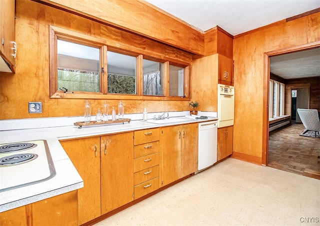 kitchen featuring baseboard heating, white appliances, sink, and wooden walls