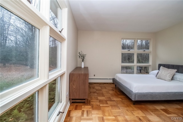 bedroom with baseboard heating, multiple windows, and light parquet floors