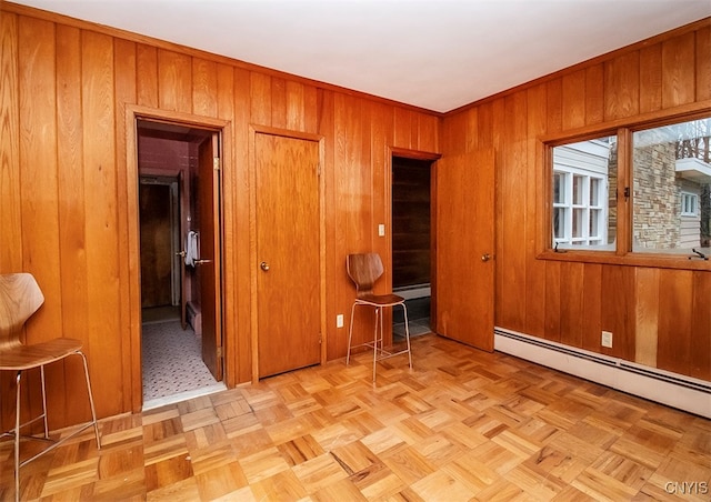 unfurnished bedroom with wooden walls, light parquet floors, and a baseboard radiator