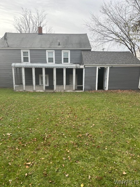 back of property with a lawn and a sunroom