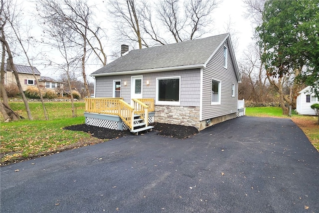 view of front of property with a deck and a front lawn