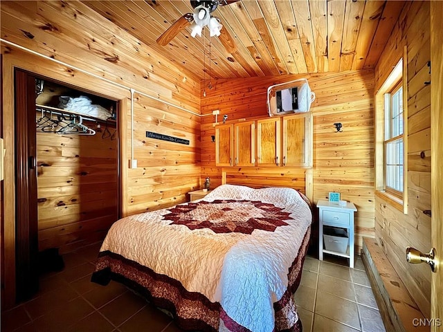 bedroom with wooden walls, dark tile patterned floors, wooden ceiling, and ceiling fan